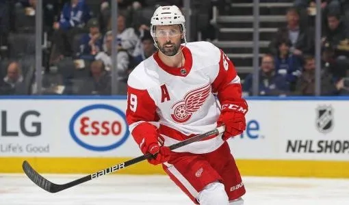 Detroit Red Wings player Sam Gagner skating during a game in full uniform, holding his stick mid-play.
