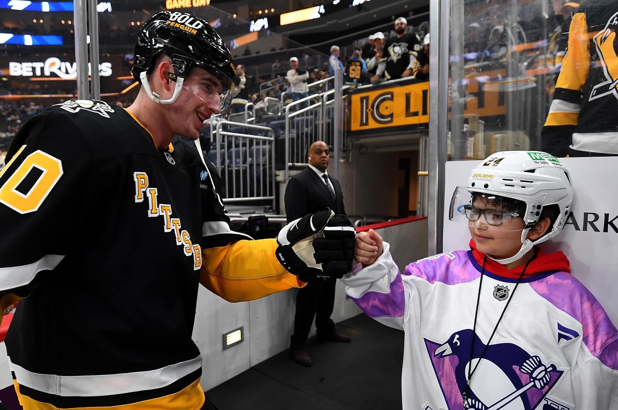 Sidney Crosby fist bumping a young ice hockey player